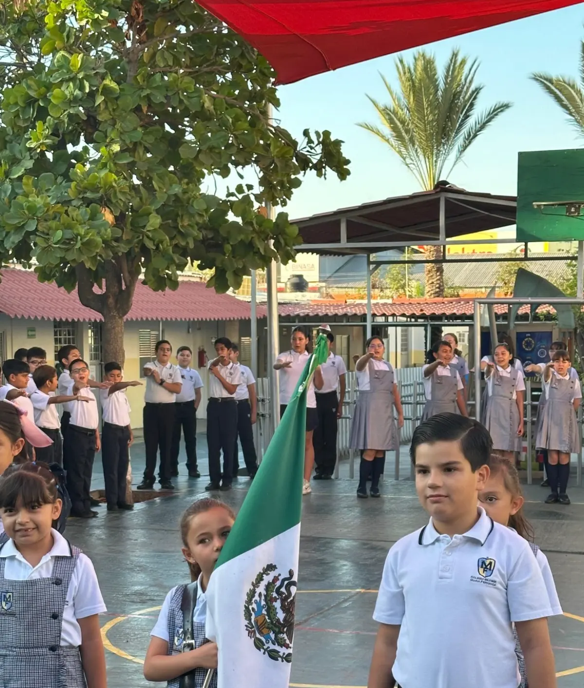 Alumnos de preescolar y primaria del Campus Cuauhtémoc en honores a la bandera en el patio