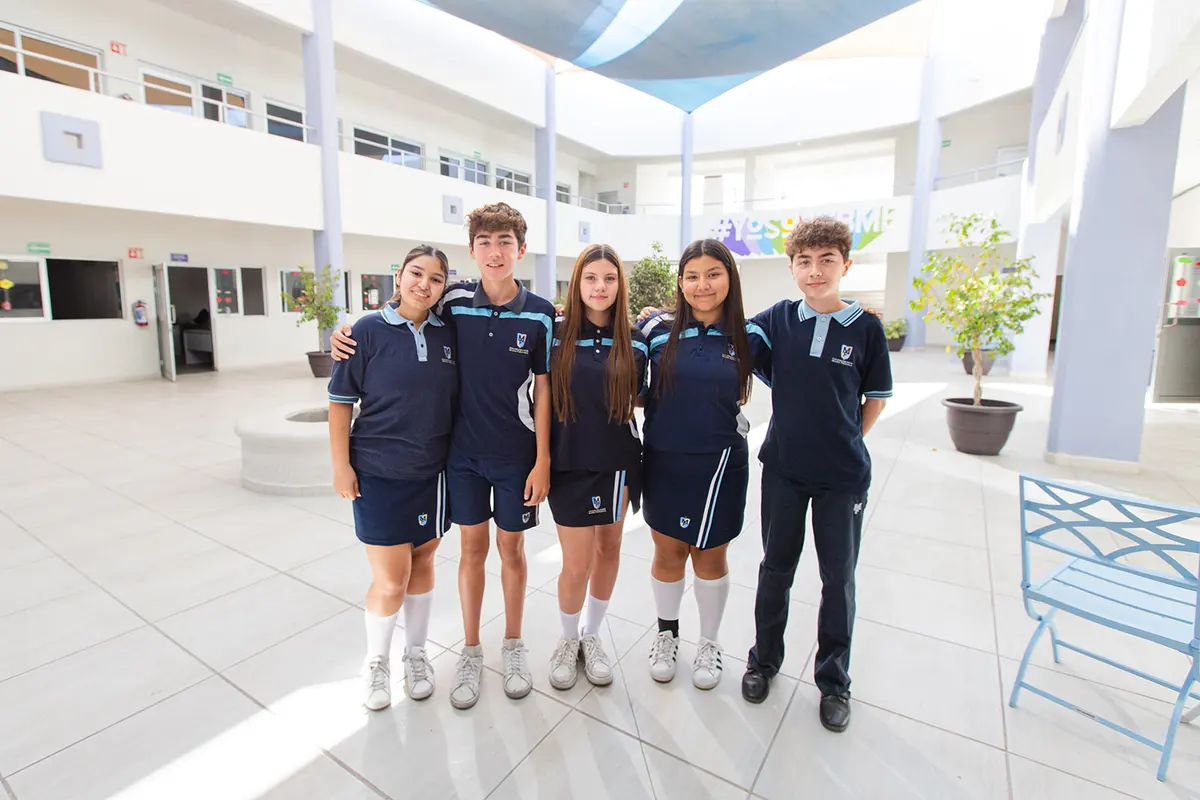 Cinco alumnos de preparatoria abrazados en el patio del Campus Garzas