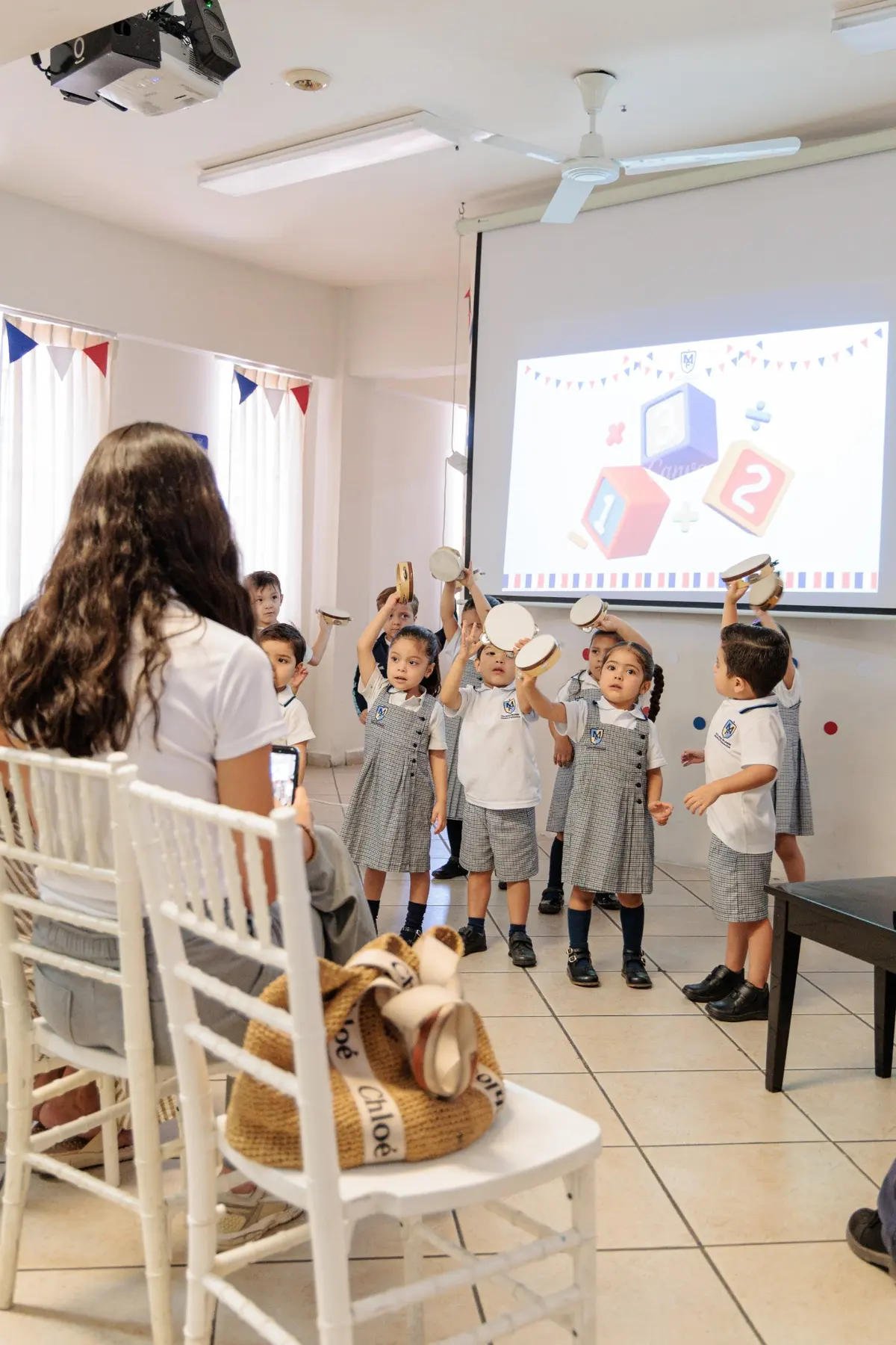 Niñas y niños de preescolar tocando panderos en clase